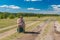 Man with old suitcase sitting on an country road and unsuccessfully waiting for any bus to pass by