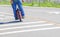 Man of one wheel skateboard rounding a corner on pavement - person is cropped and has on jeans and teeshirt