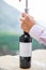 Man opening a bottle of wine, with swiss alps in the background