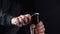 Man opening cold bottle of beer with cap on black background. Hands cracking refrigerated wheat or lager beer with an opener on