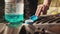 A man opens the cap of the windshield washer fluid reservoir and pours in blue anti-freeze liquid for cleaning glass