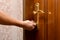 A man opens the front door by turning the handle and opening the lock