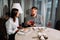 A man opens a gift box on a date.Side view portrait of laughing couple enjoying date in cafe