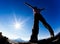 Man opens his arms in the sunshine against blue sky.