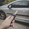 Man opens his car door with the control remote key. Male hand presses on the vehicle remote control alarm system on