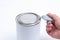 A man opens a jar of white paint with a can opener on a white background. Renovation