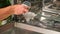 man opens salt compartment of dishwasher, pours salt into through funnel. Softening hardness water