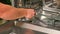 man opens salt compartment of dishwasher, pours salt into through funnel. Softening hardness water