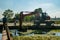 A man operated excavator crane removes debris and algae build up from the Naviglio Pavese canal on a sunny day