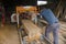 Man operates a log band saw. In a hall