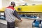 Man operating carpet automatic washing machine in professional laundry service