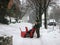 Man operating snow blower to clear driveway