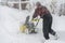 Man operating snow blower to remove snow on driveway. Man using a snowblower. A man cleans snow from sidewalks with snowblower