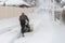 Man operating snow blower to remove snow on driveway. Man using a snowblower. A man cleans snow from sidewalks with snowblower