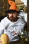 Man in orange hat with concerned face holds painted pumpkin