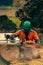 A man in an orange jacket cuts boards with an alaskan portable chainsaw mill