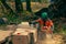 A man in an orange jacket cuts boards with an alaskan portable chainsaw mill.