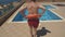 Man with orange Lifebuoy and in red swim shorts jumping to the swimming pool