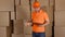 Man in orange uniform delivering heavily damaged parcel to customer. Brown cartons background. Unprofessional work and