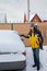 A man outside cleaning off the car after snow flurry