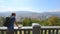 Man overlooking city from observation deck in summer, mountains skyline at back