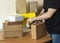 a man is packing a shipping box, a background table with shipping office boxes.