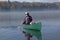 Man Paddling a Canoe with a Small White Dog in the Bow