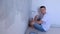 Man painter with paint roller sitting on floor looking at camera and smiling.