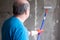 Man painting cement walls using roller brush and primer making a renovation.