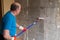 Man painting cement walls using roller brush and primer making a renovation.