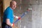 Man painting cement walls using roller brush and primer making a renovation.