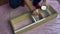 A man is painting a homemade shelf. Brush and white paint