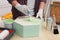 Man painting honeycomb shaped shelf with brush at wooden table indoors, closeup