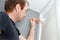 A man paints the wall with white paint in the apartment. Repair your home