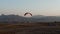 Man with the parachute catching the wind while standing on the rock face