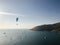 A man on a parachute flies over the sea against the backdrop of a beautiful sunset, islands and yachts.