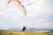 A man paraglider taking off from the edge of the mountain with fields in the background. Paragliding sports