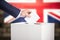 A man participates in the democratic process by placing her vote into the ballot box with the British flag in the background