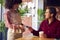 Man Paying Female Server In Coffee Shop Using Debit Or Credit Card