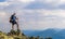 Man on peak of mountain. Emotional scene. Young man with backpack standing with raised hands on top of a mountain and enjoying mo