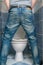 Man peeing to toilet bowl in restroom from back