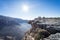 Man peeking over the cliff with the sun in the background at the Grand Canyon of Jebel Shams, Oman