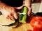 Man peeling a cucumber on a wooden board.