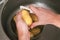 A man peels potatoes with a vegetable peeler in the sink. Preparation of potatoes for cooking. Cleaning peel from