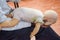 Man performing CPR on baby training doll dummy with one hand compression. First Aid Training - Cardiopulmonary resuscitation.