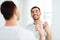 Man with perfume looking to mirror at bathroom