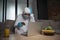 Man in personal protective equipment and medical mask using laptop and holding credit cards near fruits and glass