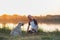 Man pets his dogs in the nature at sunset by the lake.