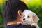 Man petting cute maltese puppy on his shoulder