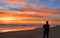 Man with phone on the beach at sunrise.